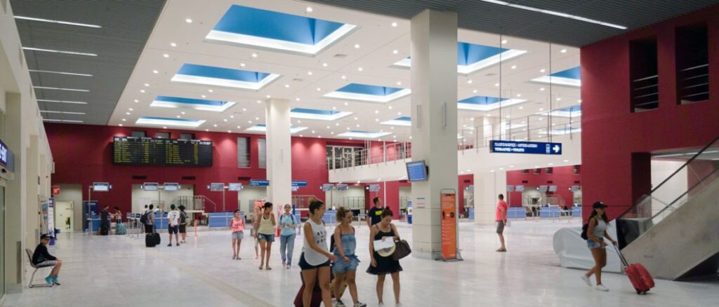 People walking aorund  Greek airport. 