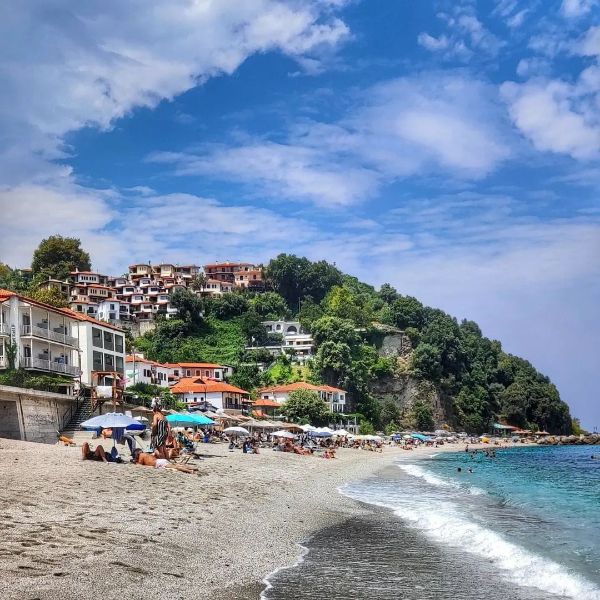 Agios Ioannis seafront village with swimmers. 