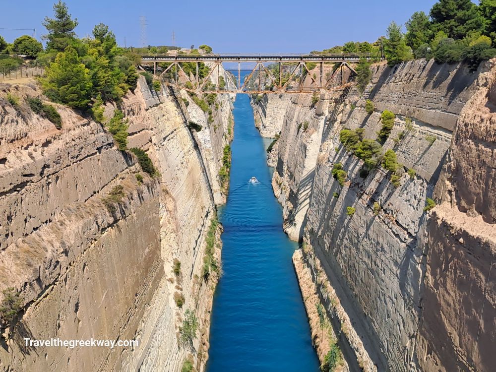 The Corinth Canal with steep rock walls and a bridge overhead, connecting the Ionian and Aegean Seas.