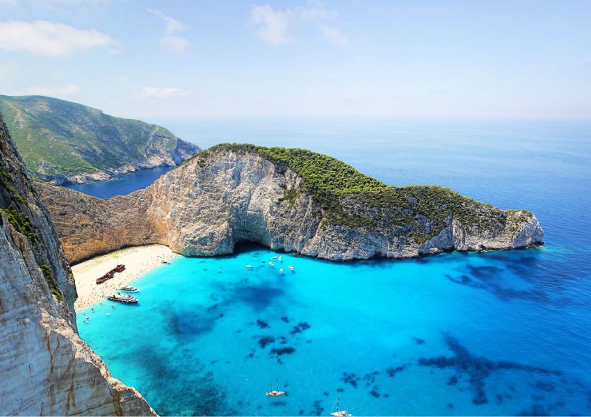 Things to Do on Zakynthos Island, the Navagio beach with a lot of boats and swimmers. 