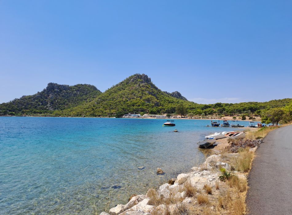 Things to Do in Loutraki Greece. The turquoise Vouliagmeni lake with small boats and forested hills view around