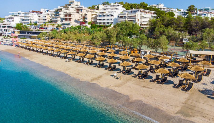 Vouliagmeni beach with many umbrellas and beds in Athens Greece.