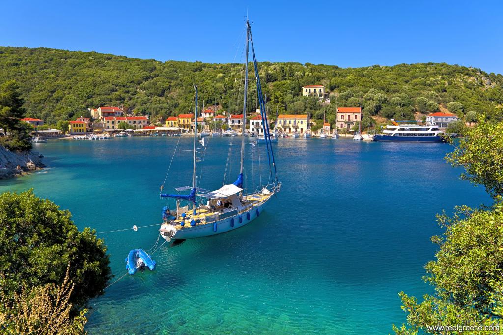The charming harbor of seafront Frikes village in Ithaca Greece, featuring traditional waterfront architecture, vibrant flowers, and a yacht, creating a tranquil and inviting atmosphere.