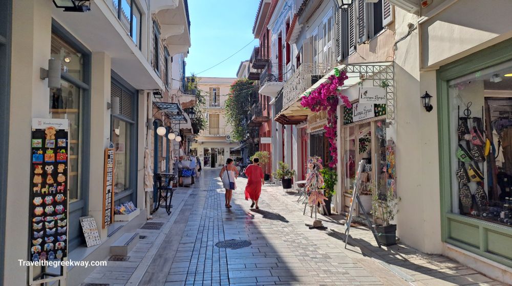 Two women walking in the pedestrianized alley of Nafplio lined with touristic shops.