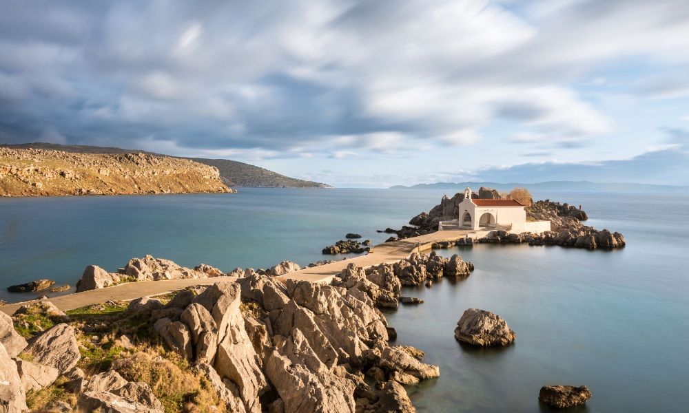 Agios Isidoros Beach with a narrow pathway and a church at the end of it in Chios. 