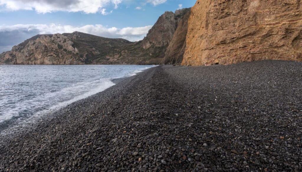 The black pebbled beach of Mavra Volia with rocky background.