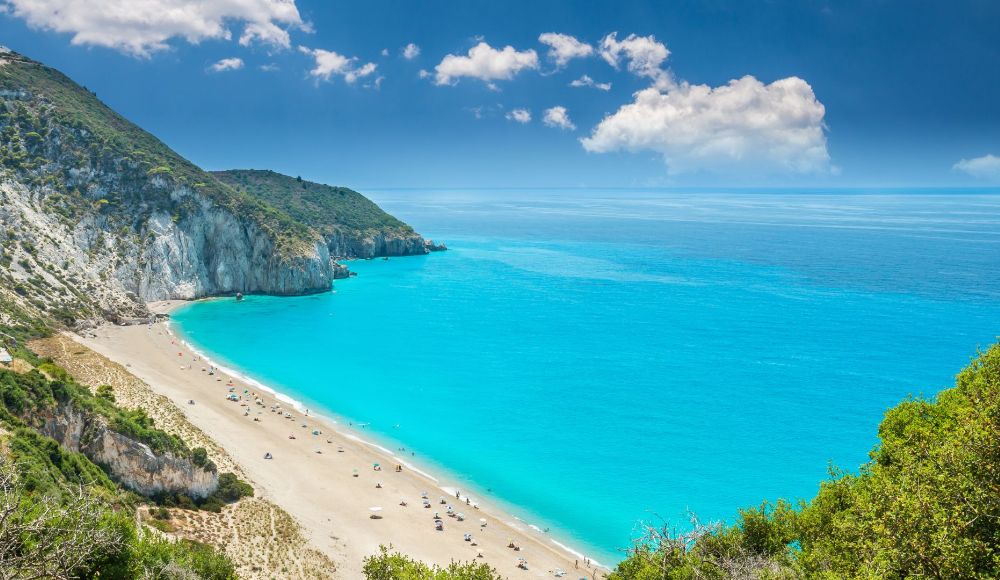 Things to do in Lefkada Greece: Long Milos beach with light blue waters and people by the beach