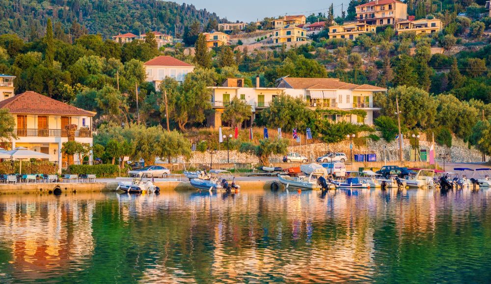 Some houses beside the beach and boats in the sea in Nydri. Best Places to Go to Greece in April.