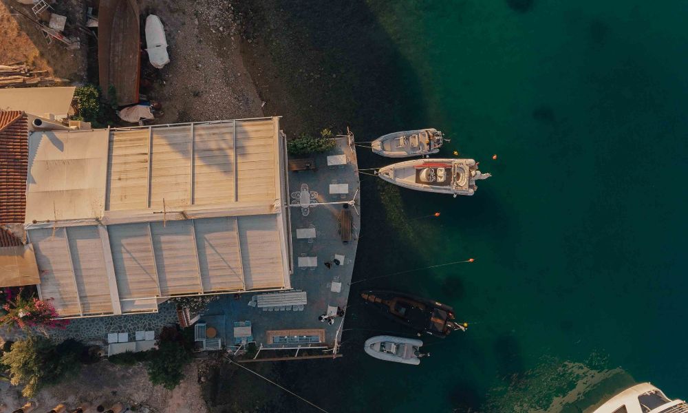 A view from a drone from a small port with four boats in the sea.