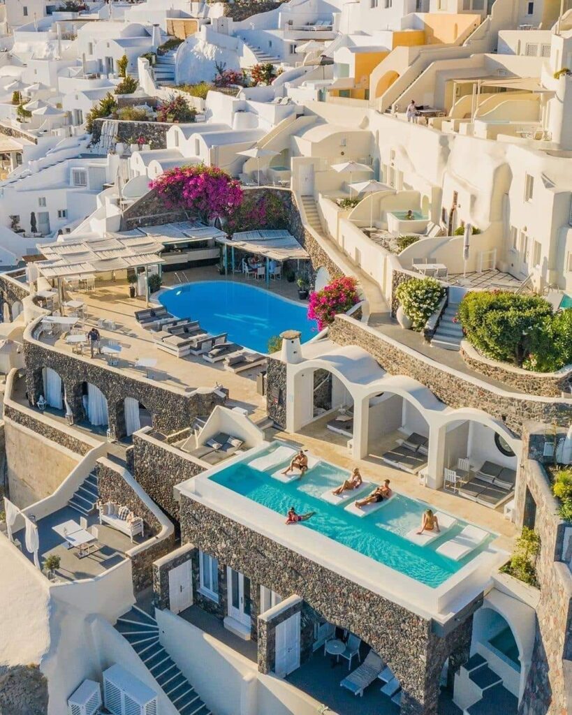 Canaves Oia Suites & Spa in Santorini ilsnad greece with a swimming pool and people lying on beds, 