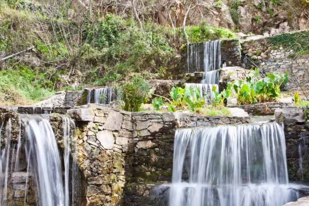 Beautiful waterfalls at Argyroupoli Springs in Rethymno, Crete, cascading over stone terraces surrounded by lush vegetation.