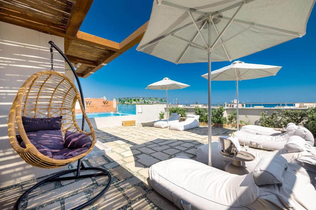 Modern rooftop terrace at White Swan Hotel in Rethymno, Crete, featuring comfortable seating, umbrellas, a hanging chair, and a view of the pool and sea."