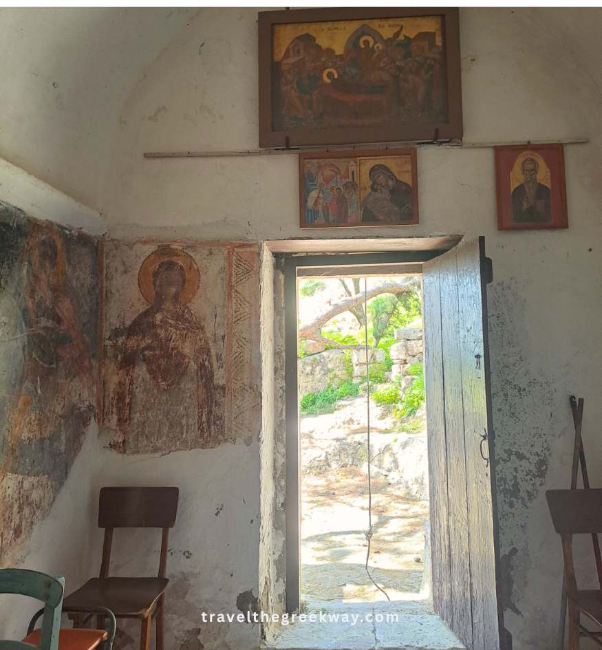 Historic interior of a Byzantine church in Paleachora on Aegina Island, Greece, featuring ancient frescoes near an open doorway.