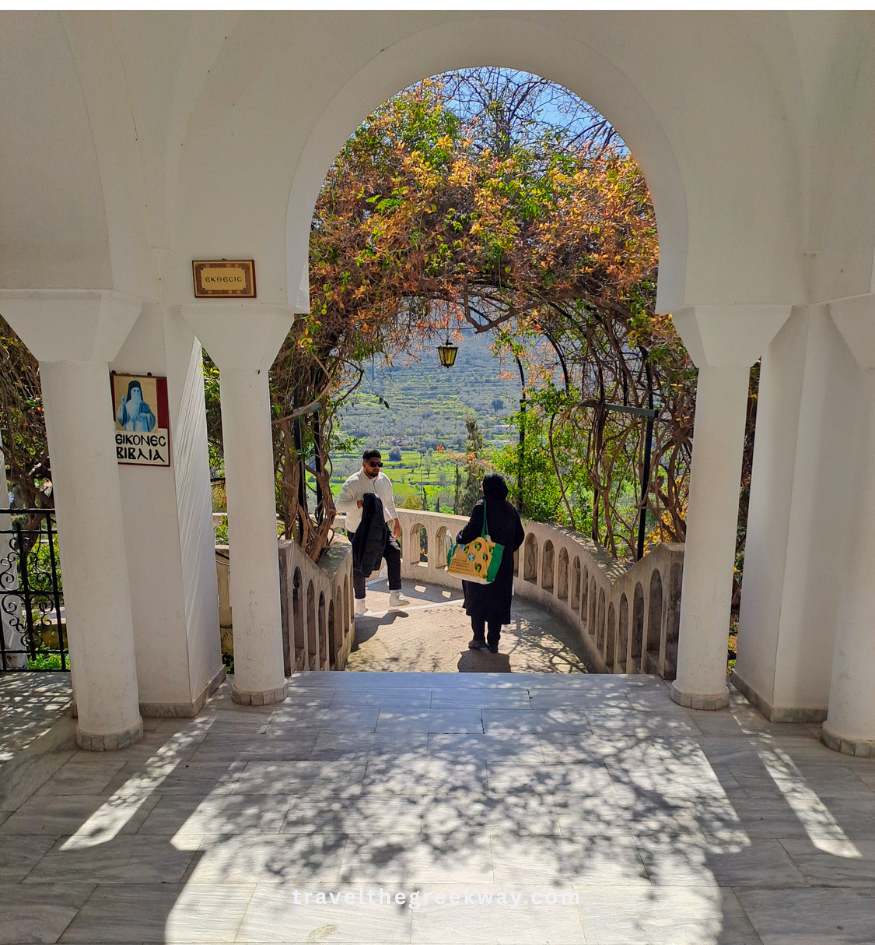 A scenic view through a white arched gateway at the beautiful Agios Nektarios Monastery on Aegina Island, Saronic Gulf, Greece.