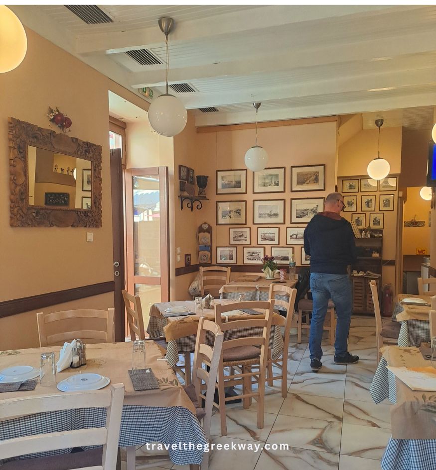Cozy interior of a traditional tavern on Aegina Island, Saronic Gulf, Greece, with wooden tables, checkered cloths, and framed pictures.