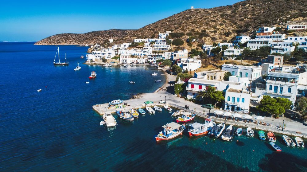 Port of Katapola with many boats in the sea and whitewashed houses in a sunny day in Amorgos Island Greece.