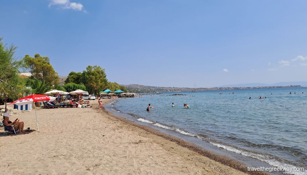 Marathonas A Beach in Aegina with many swimmers and people under umbrellas.