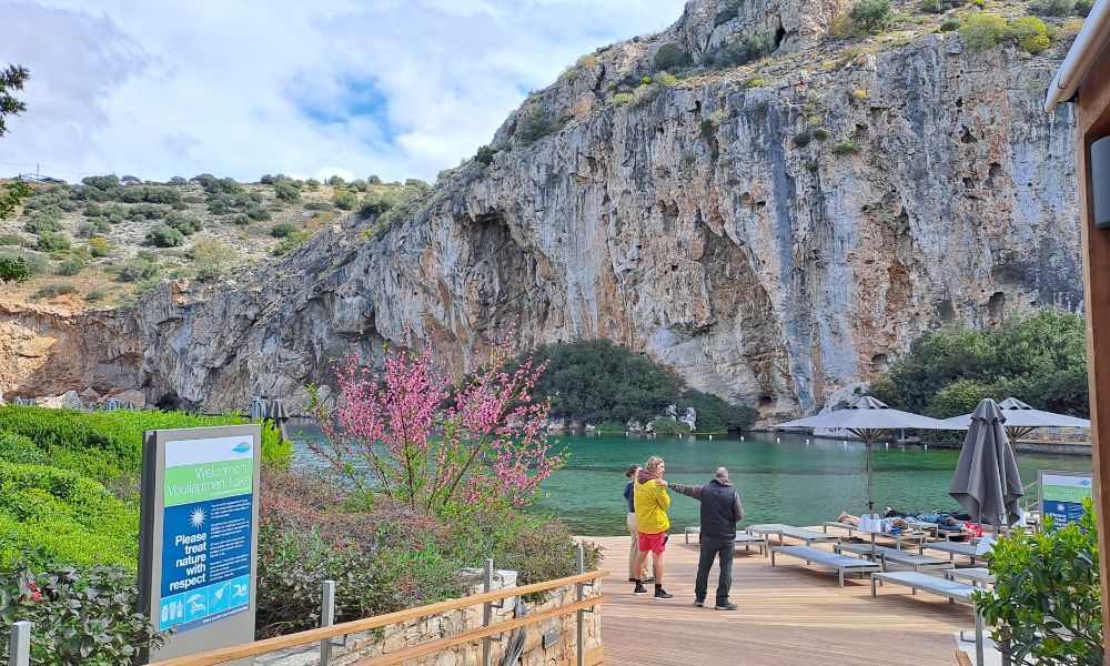 Etrance to Vouliagmeni Lake with three persons, umbrellas and green in Athens Greece. 