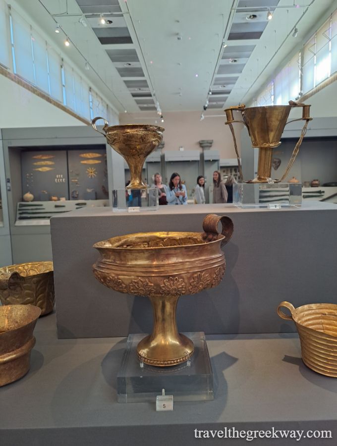 Display of ancient golden cups from Mycenae, Greece, showcasing intricate designs and craftsmanship in a museum.