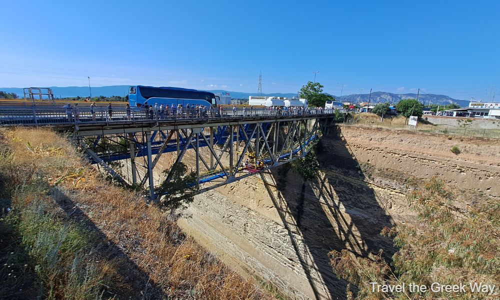 The bridge of Corinth Canal with cars and people crossing it near Ancient Corinth. 