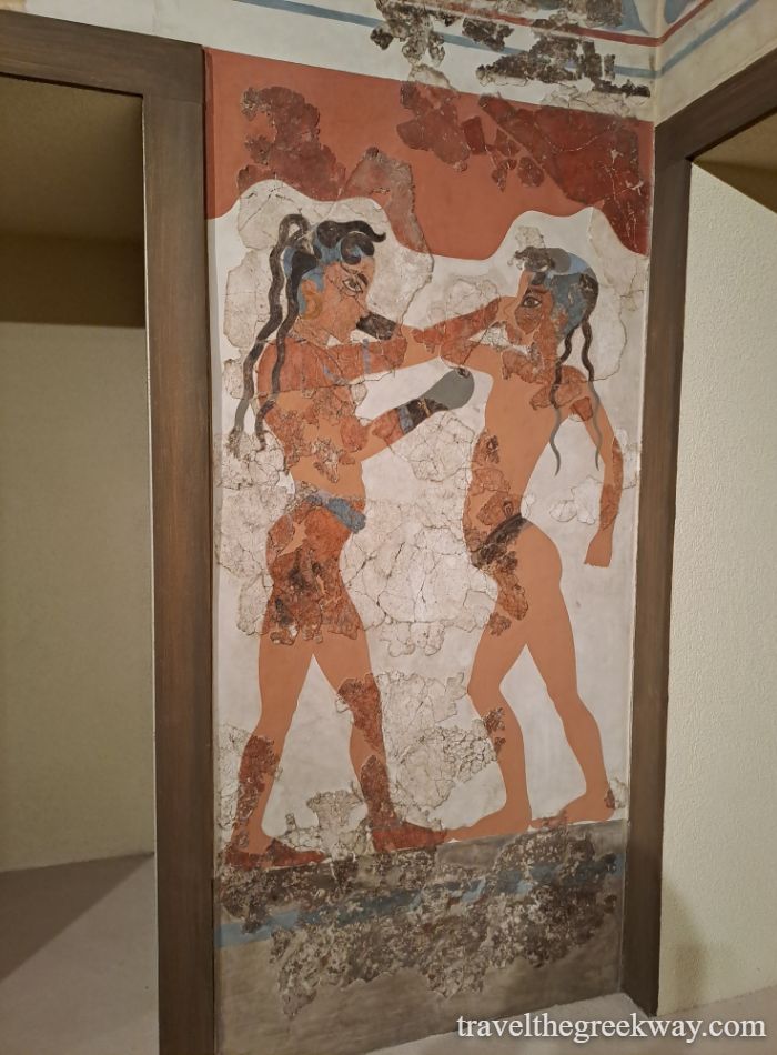 Ancient fresco of two boxers from Santorini, Thera, in warm earth tones, exhibited at the Mycenae museum.