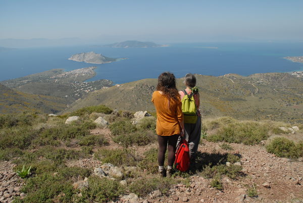 Two women hikers looking at the vistas on a mountain in Aegina. 