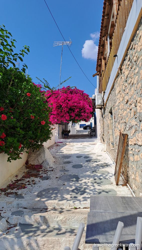 A whitewashed alley with bougainvillea flowers in Aegina. 
