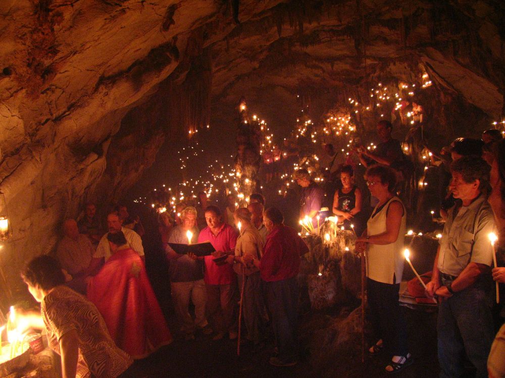 Cave Church of Agios Ioannis and people with lit candles