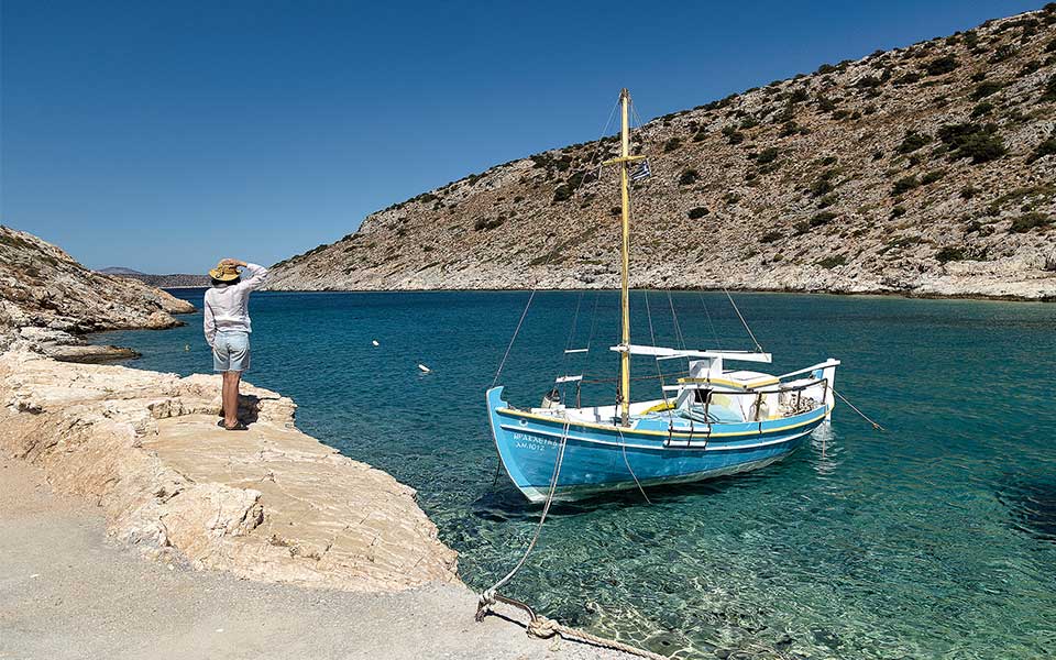 Tourkopidago beach,with a small fishing boat and a woman standing