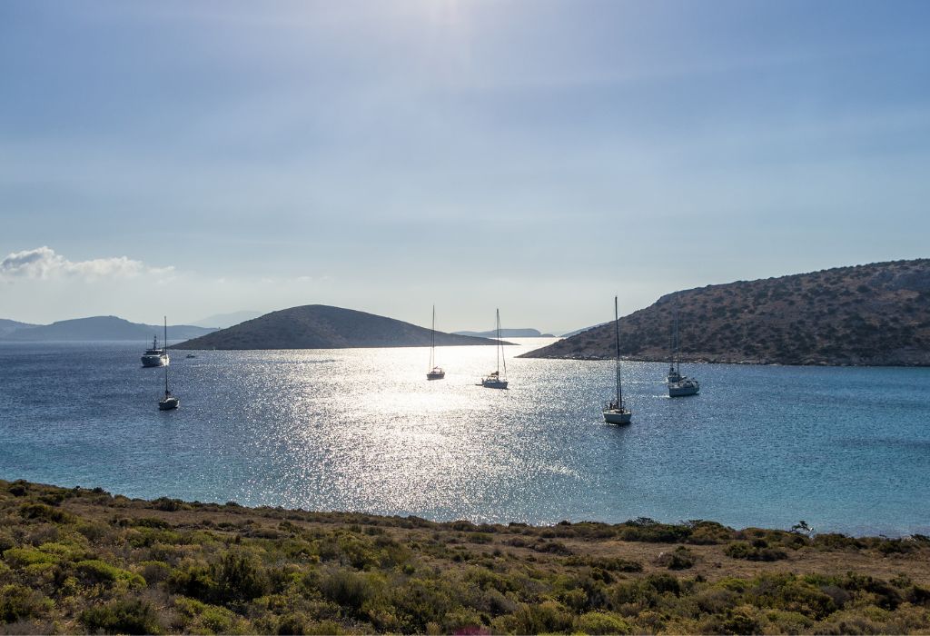 A few yachts are scattered in a bay in Iraklia Greece