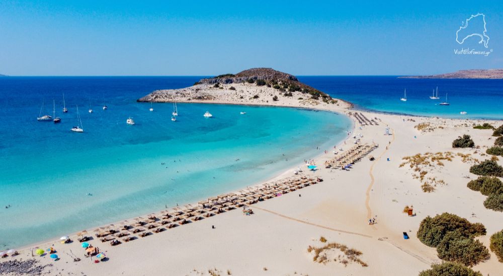The sandy beach of Simos with beds and umbrellas  and yachts in Elafonisos