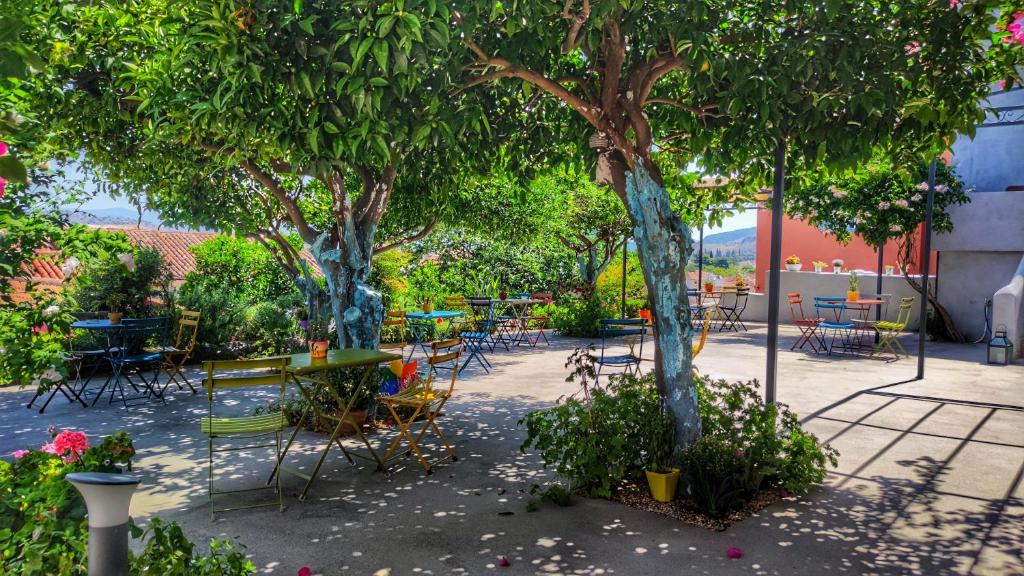 The oragnge garden with colorful tables and chairs of Aethra Boutique rooms in Greece. 