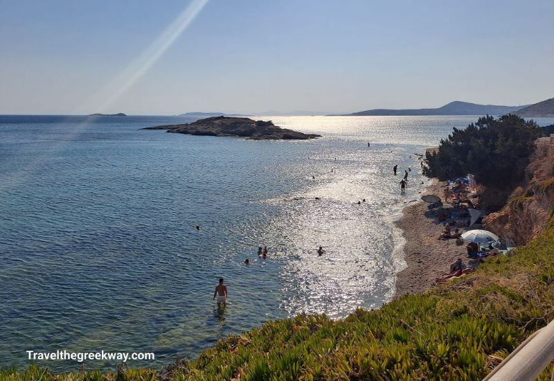 A sandy beach with a few people swimming in Athens Riviera Greece.
