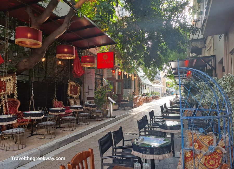 A pedestrian with chairs and bars along the road in Pysrri area Athens.