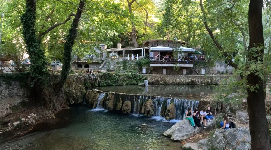 The Erkyna river in Krya Nera of Livadia Greece with young people sitting around and the Xenia Cafe. 