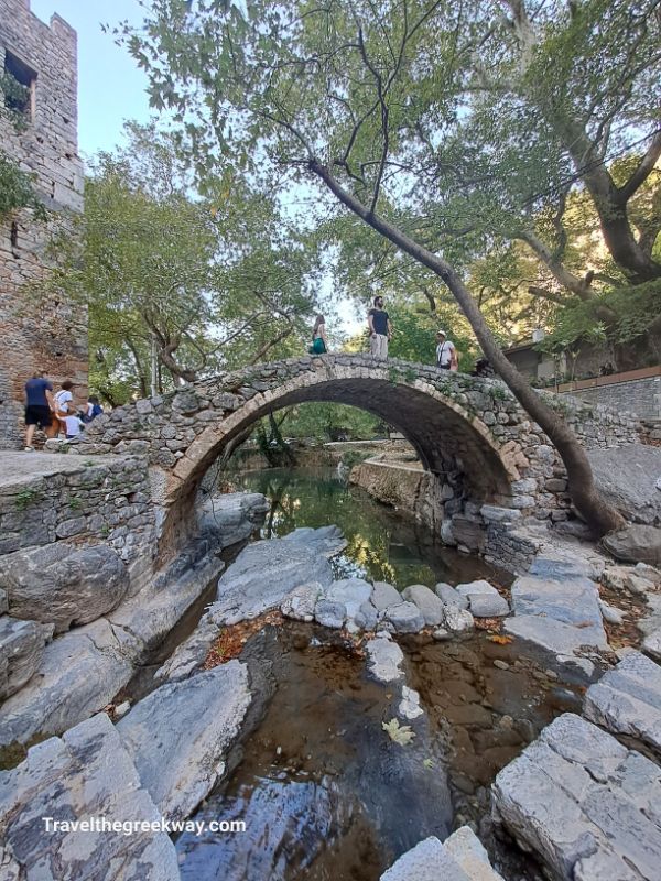 A stone bridge with people in Krya Springs in Livadia Greece. 