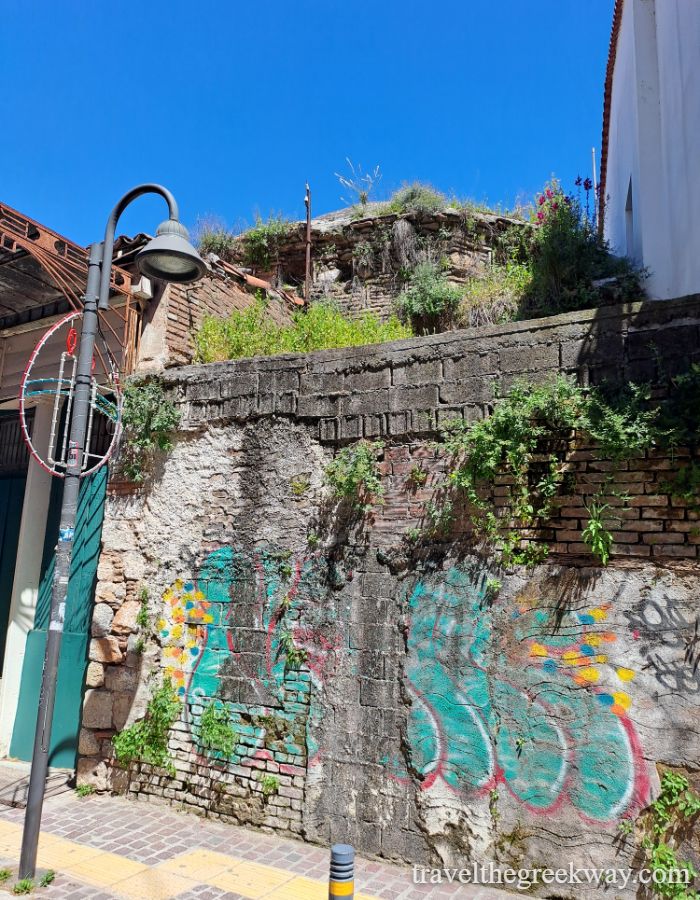 Colorful street art on an old stone wall of a mosque under a clear blue sky in Livadia, Greece.