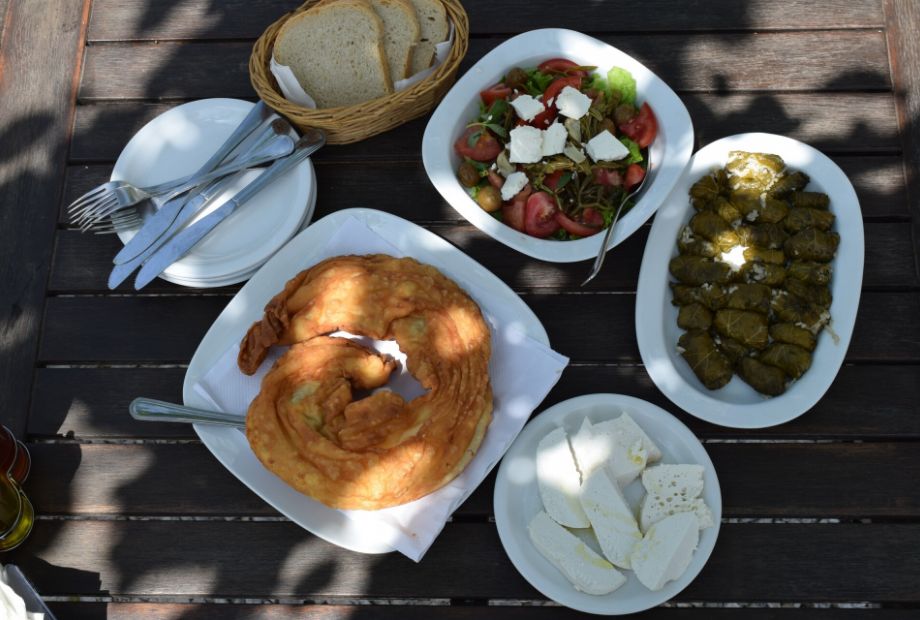 A table full of Greek delicacies: Alonissos cheesepie, local goat cheese, dolmadakia and Greek salad.