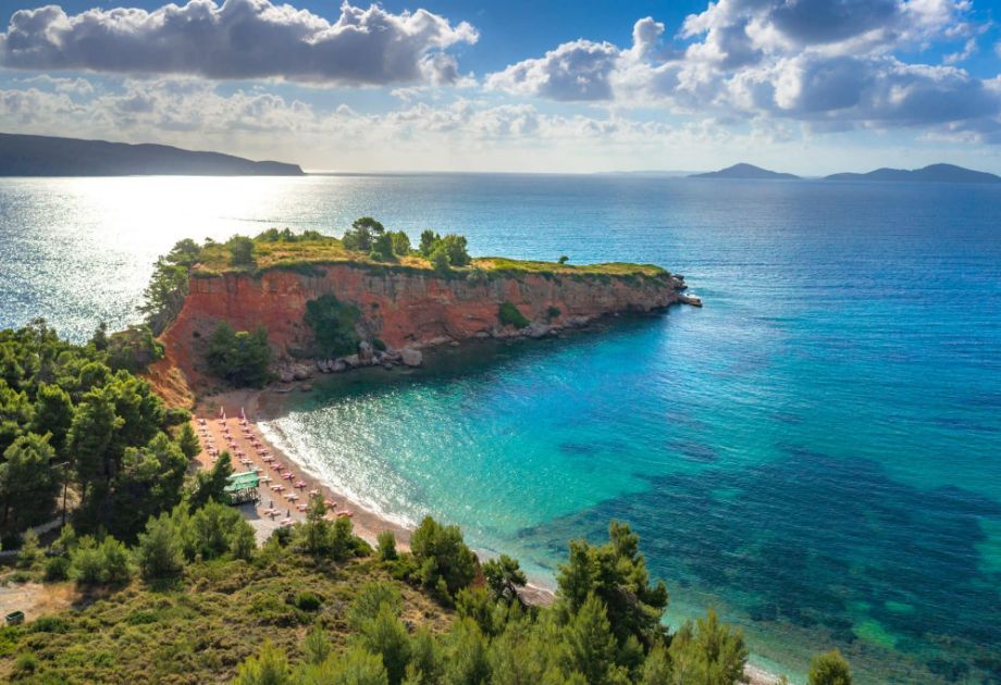 An aerial view captures the breathtaking beauty of a hidden gem beach on Alonissos Island, nestled between rugged cliffs and surrounded by untouched nature