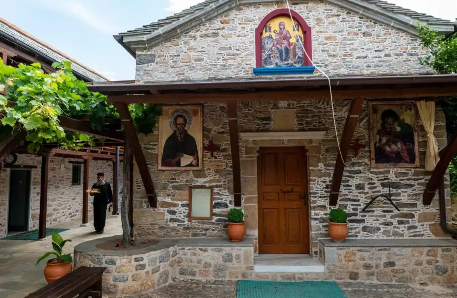 The stone built old Monastery of Kyra Panagia with icons on the walls and a monk walking. 