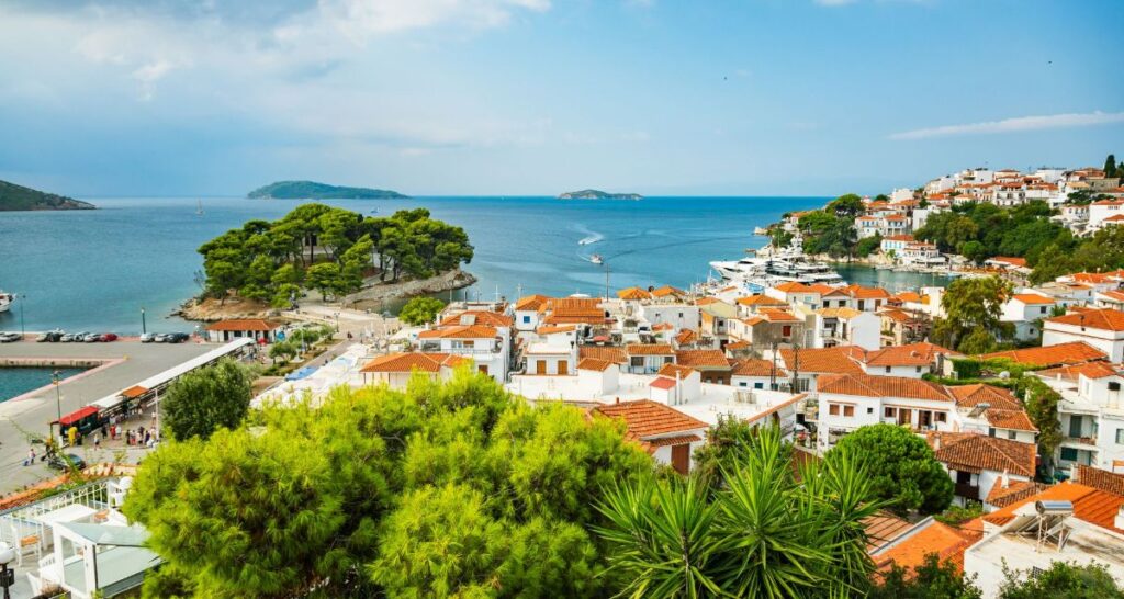 A captivating image capturing the essence of Skiathos town, with its distinctive tiled roofs adding character to the skyline and quaint, winding alleys offering glimpses of local life and culture.
