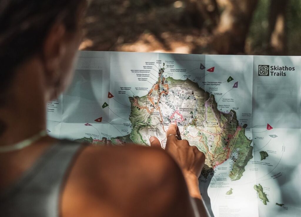 A woman pointing at a paper hiking map in Skiathos Greece. 