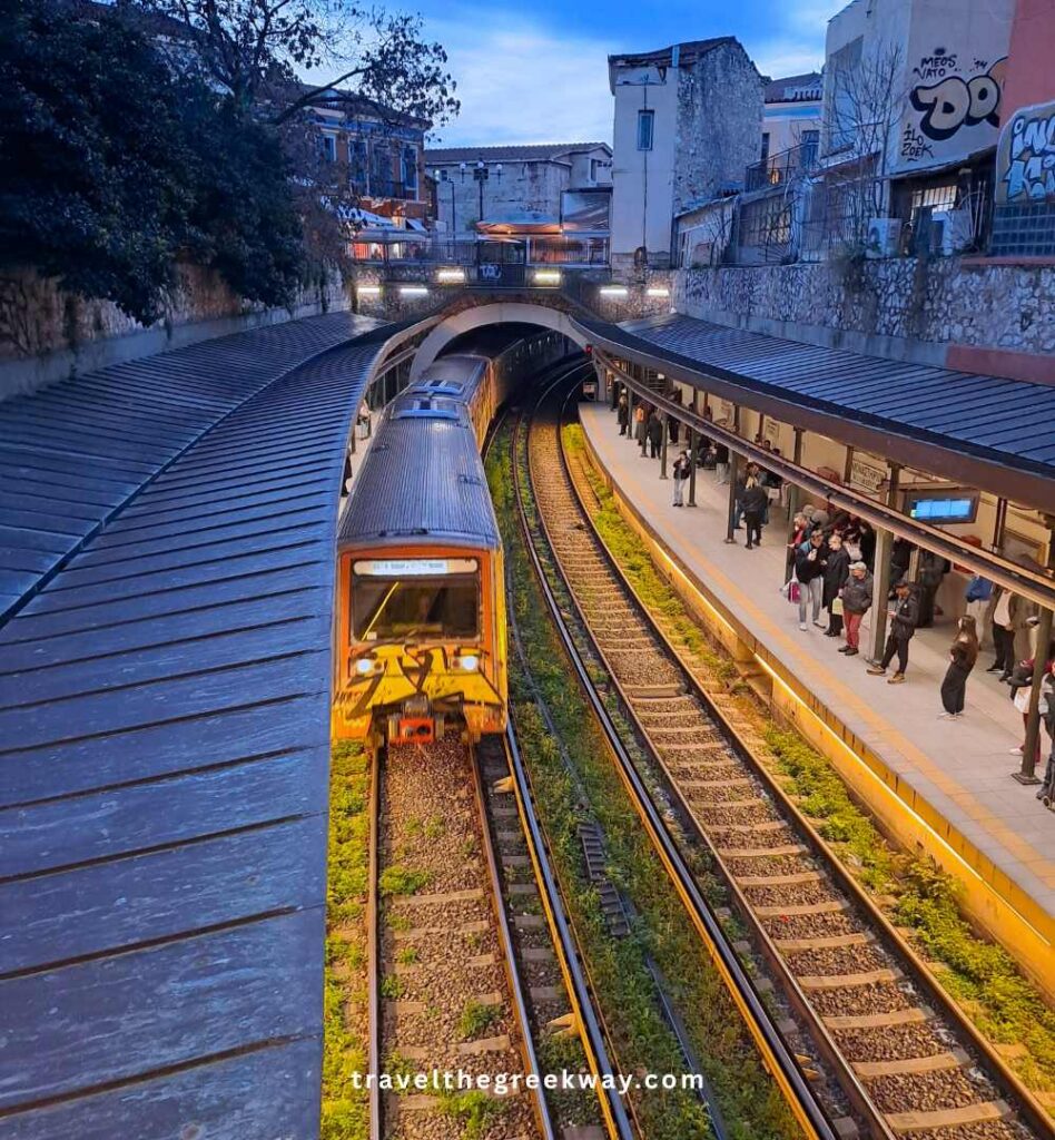 Athens metro train arriving at an underground station with passengers waiting on the platform during early evening.
