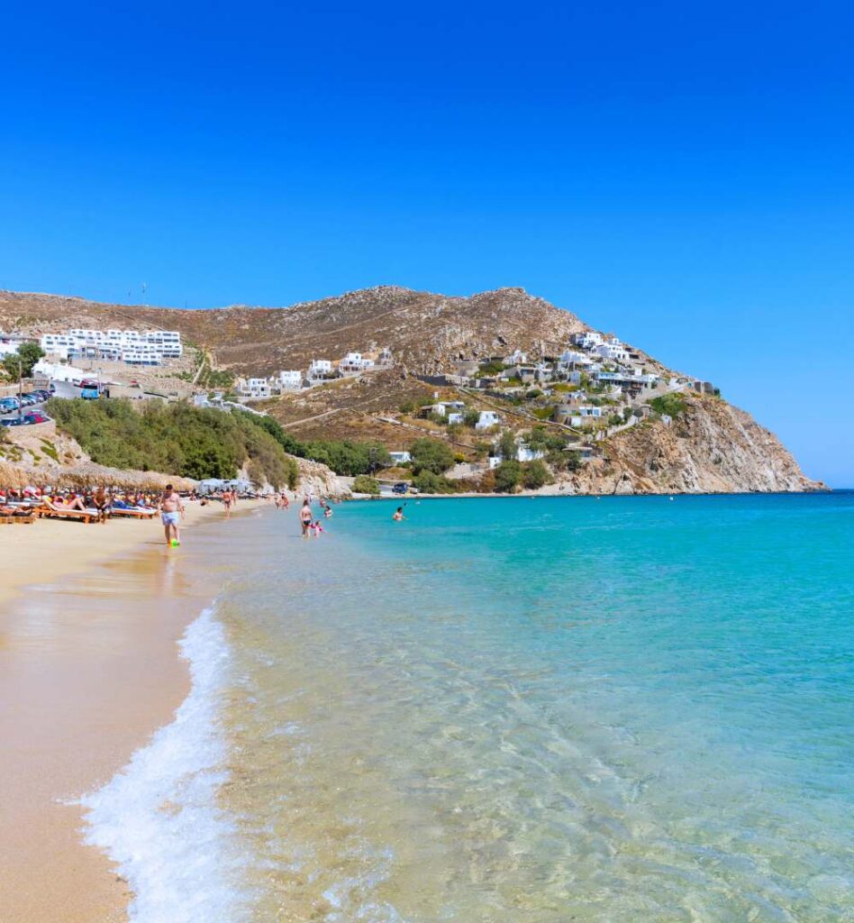Elia Beach in Mykonos with clear turquoise water and sunbeds along the sandy shore.