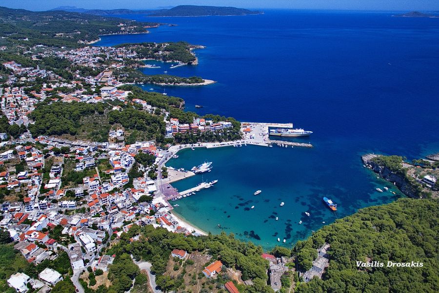 An aerial perspective of Patitiri port on Alonissos Island, surrounded by lush greenery and hillsides. 