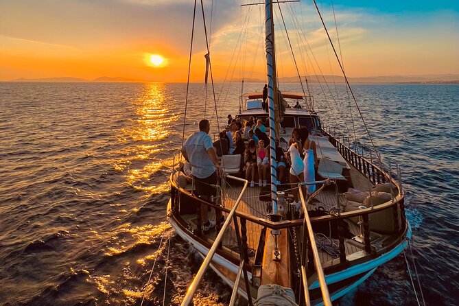 Group enjoying a sunset cruise on a sailboat in Athens Riviera, with a stunning sunset over the sea.