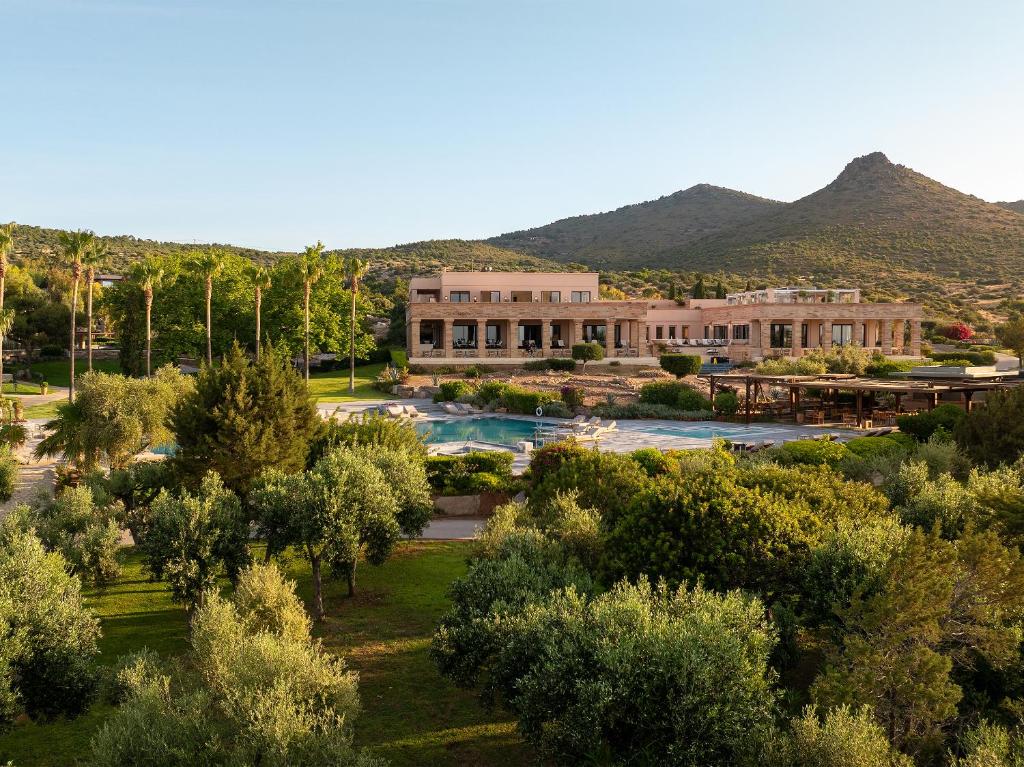 Cape Sounio Grecotel Boutique Resort in Athens Riviera, nestled among lush greenery with a pool and mountains in the background.