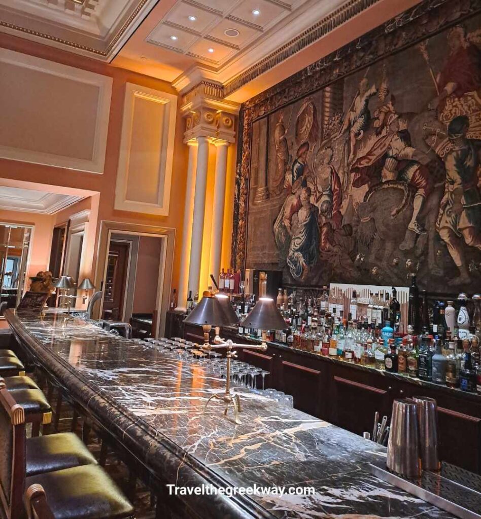 The upscale Alexander’s Bar at the Hotel Grande Bretagne, featuring a marble counter and large tapestry.