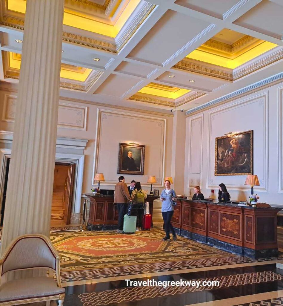 Elegant reception desk at the Hotel Grande Bretagne, decorated with classical oil paintings and rugs.