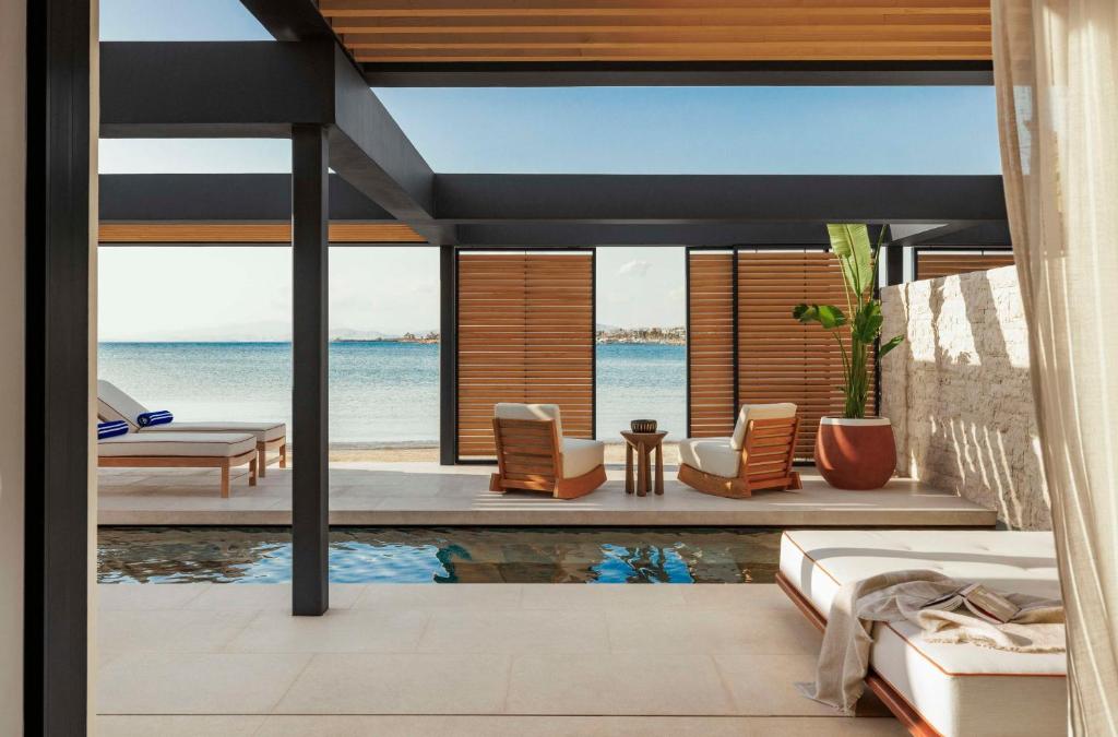 A luxurious beachfront setup at One&Only Aesthesis Hotel in Glyfada, Athens Riviera, with a private pool and lounge chairs overlooking the sea.